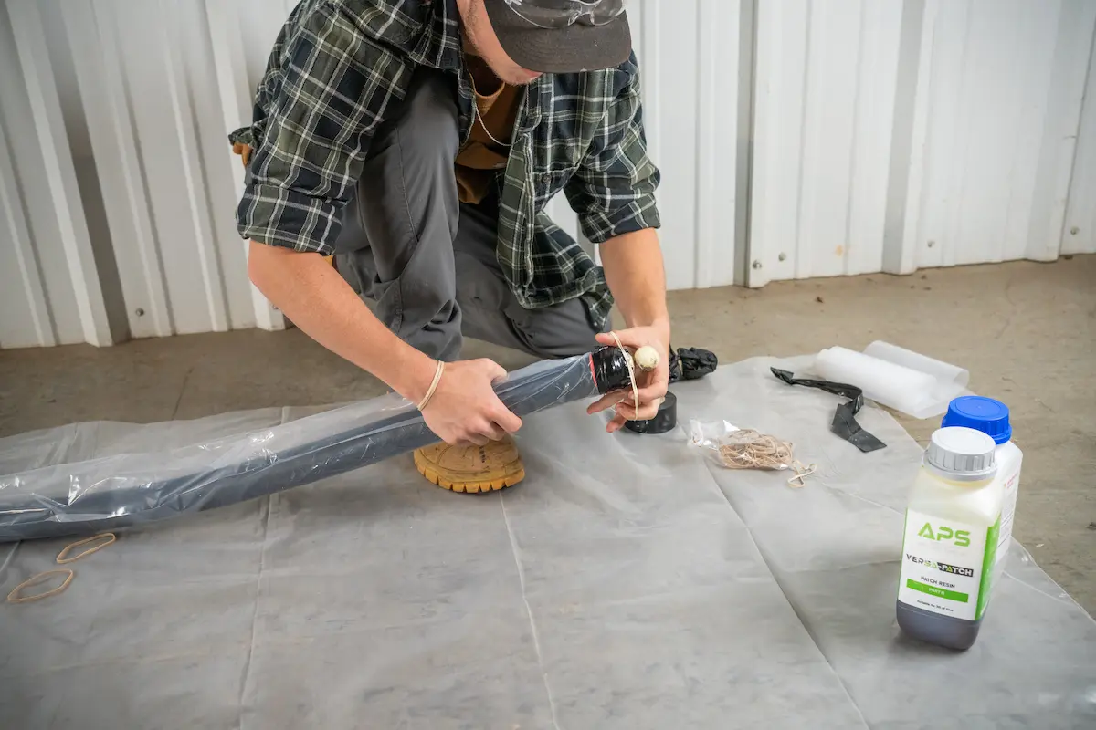Technician preparing a CIPP packer with APS Versa-Patch resin during a trenchless pipe repair installation.