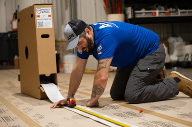 APS technician measuring CIPP liner dispensed from a Protect & Pull liner storage system during preparation for trenchless pipe lining.