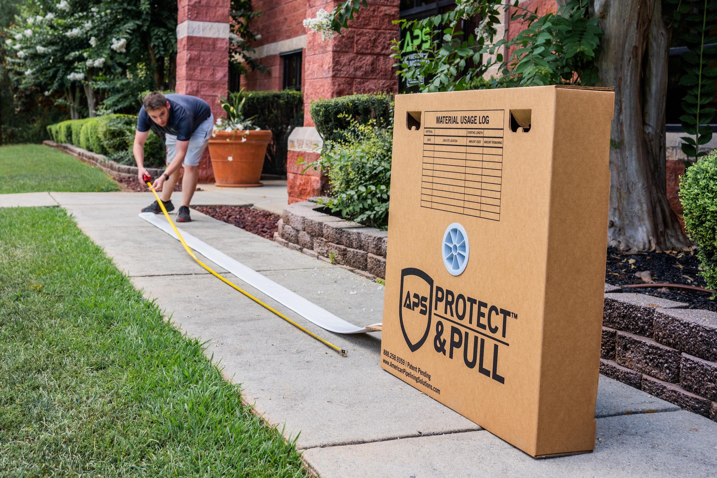 A worker using the APS Protect & Pull system to prep a liner outside a job site, next to the Protect & Pull box