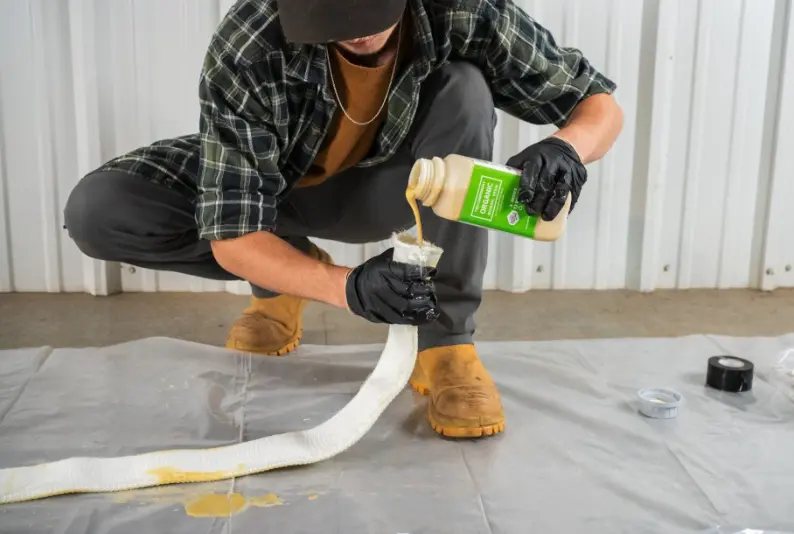 Contractor pours Versa-Patch resin into fiberglass patch during trenchless pipe repair preparation.