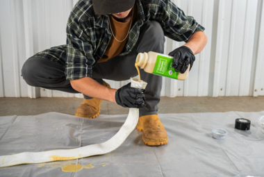 Contractor pours Versa-Patch resin into fiberglass patch during trenchless pipe repair preparation.