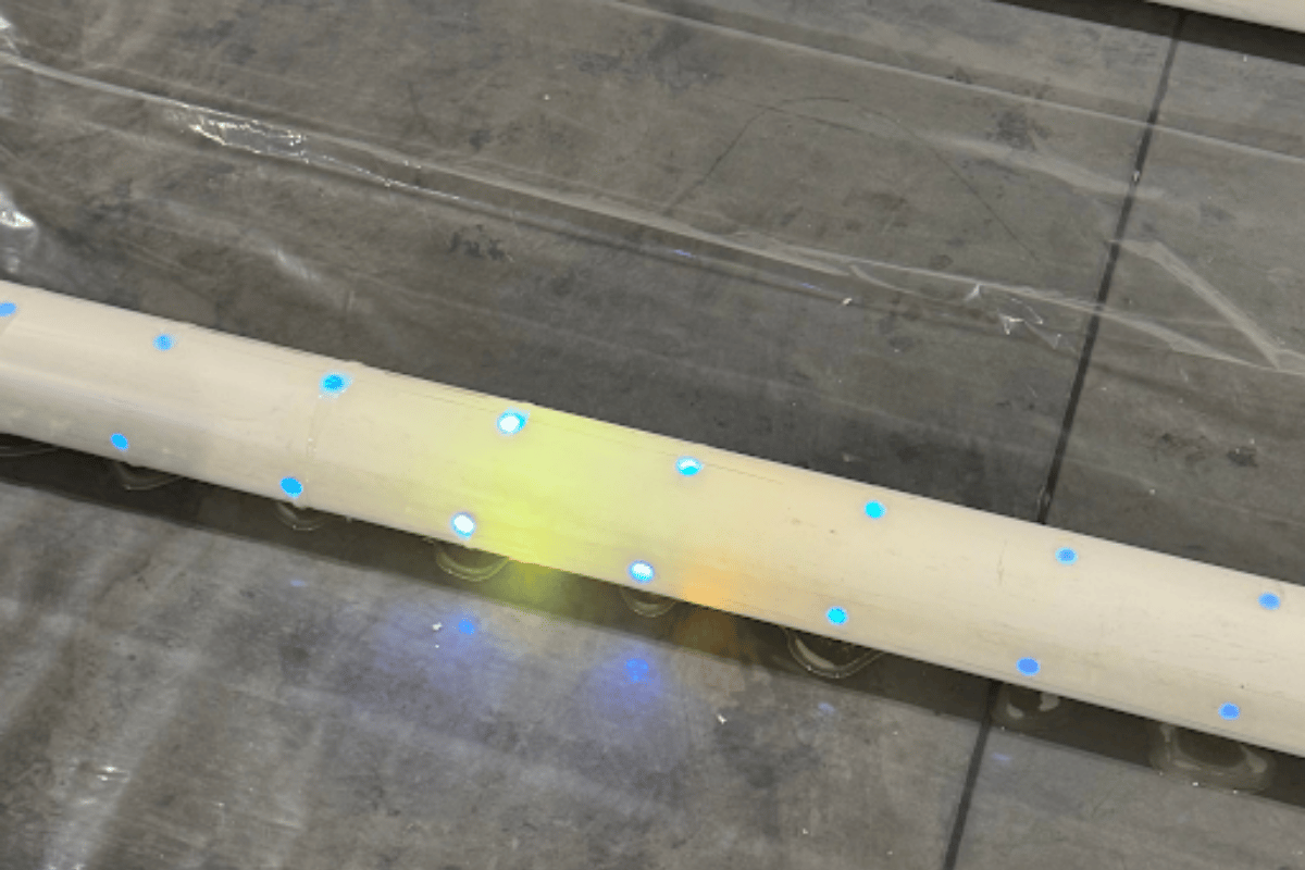 Close-up of a UV curing light system inside a pipe during a trenchless CIPP installation, showing illuminated curing points along the liner as the resin cures